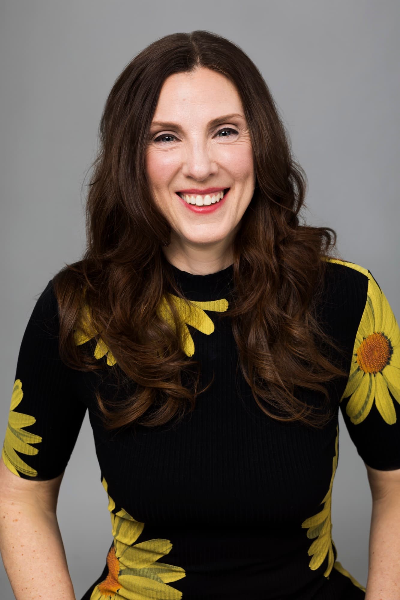 Portrait professionnel de Marie-Pierre Poirier, humoriste québécoise, avec un chandail noir à fleurs jaunes.