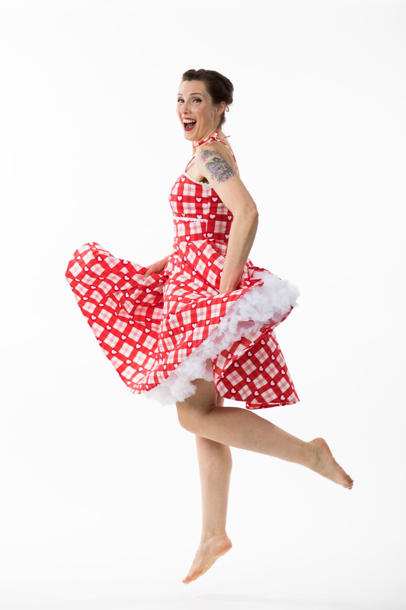 Marie-Pierre Poirier humoriste en robe rouge, souriante et en mouvement sur scène.